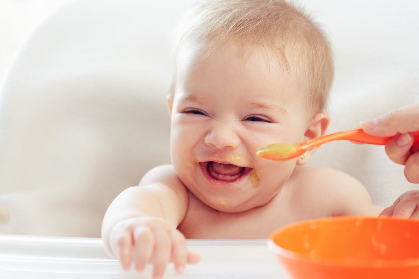 Parent feeding a baby complementary food at the table